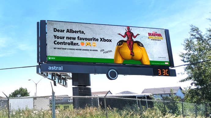 A photo of a billboard showing Deadpool sat on an Xbox controller shaped like Wolverine’s butt.