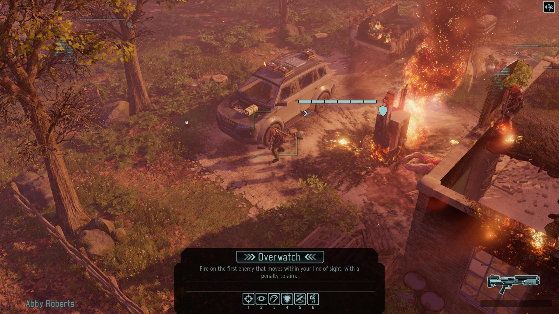 A player ducks in cover near a fire at a woodland garage