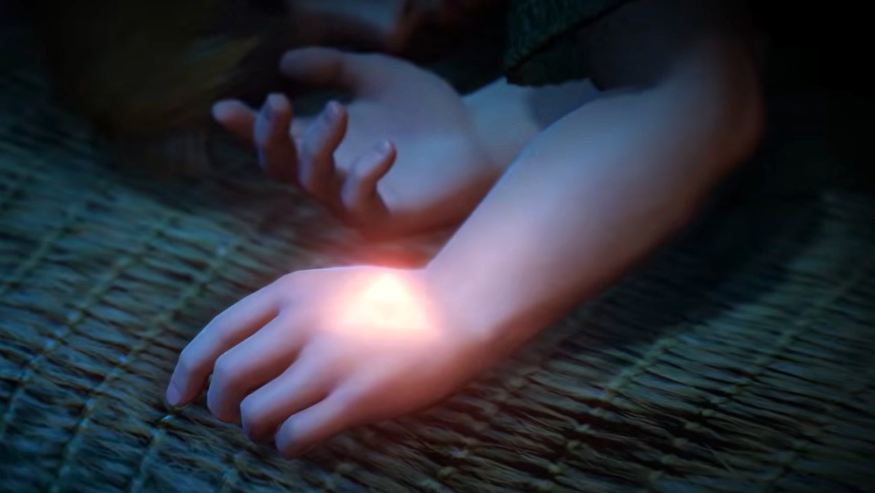 Teaser image for The Legend of Zelda: Ocarina of Time's Switch 2 remake showing a close-up of the Triforce glowing on a sleeping Link's hand.