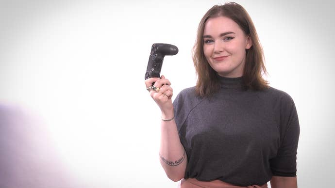 Eurogamer’s Zoe Delahunty-Light, standing facing the camera and holding a game controller up.